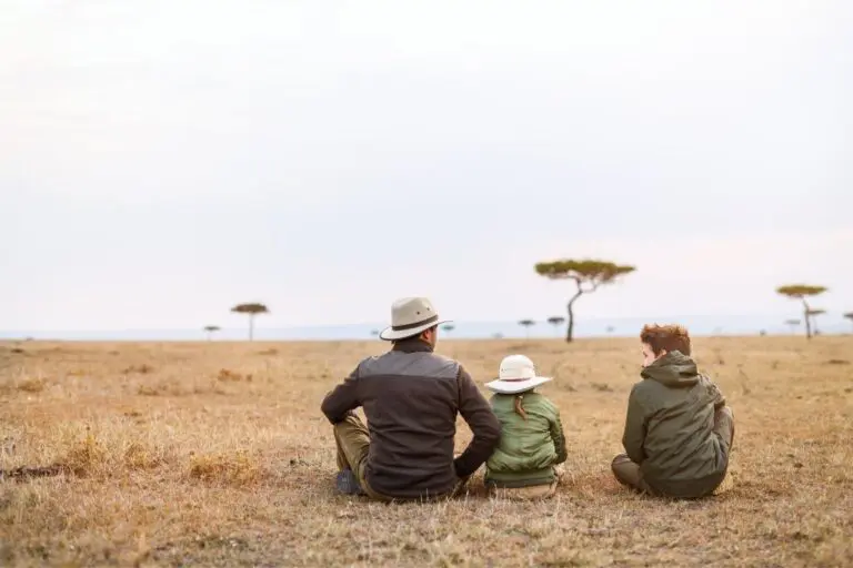 family sitting in safari landscape looking at acacia trees