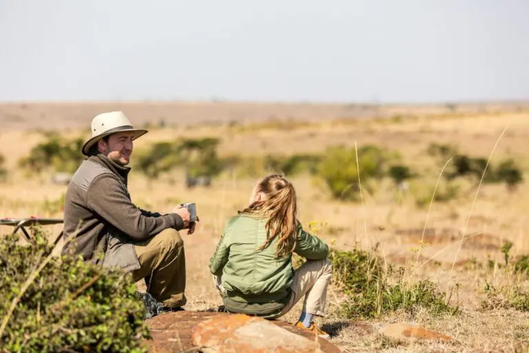 man and woman relaxing on safari in dry savanna landscape