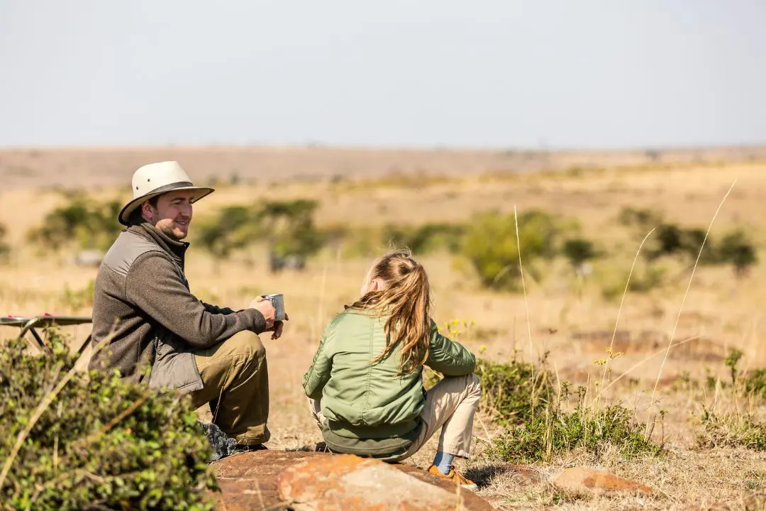 man and woman relaxing on safari in dry savanna landscape