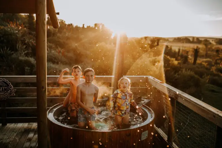 three children playing in a hot tub at sunset