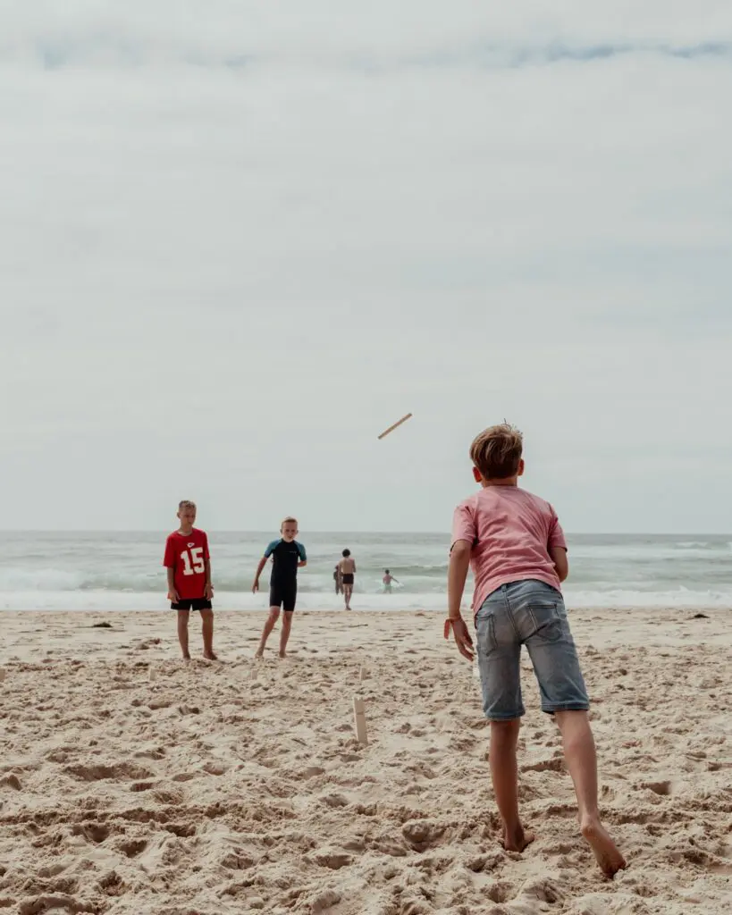 kids playing beach cricket on a cloudy day