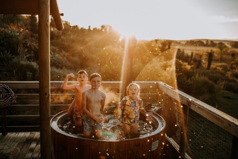 three children playing in a hot tub at sunset
