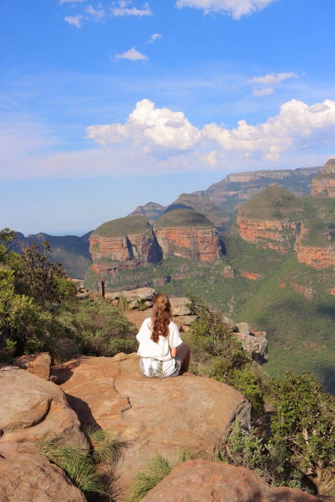 woman sitting on cliff edge overlooking blyde river canyon