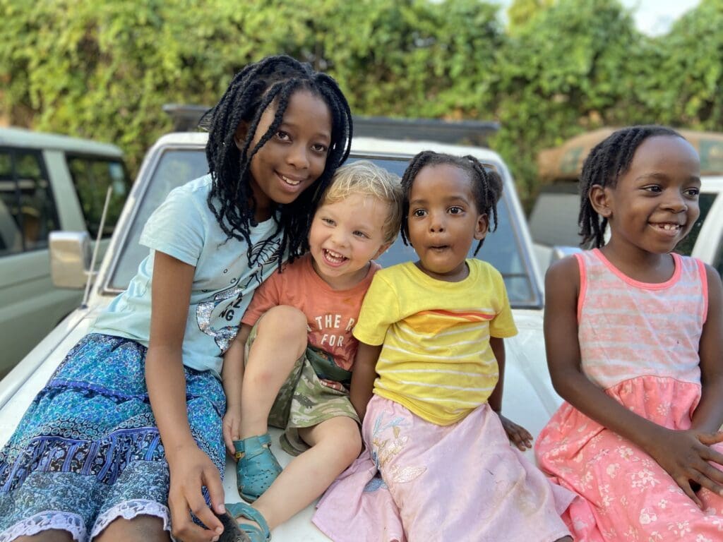four happy children sitting on a white safari vehicle