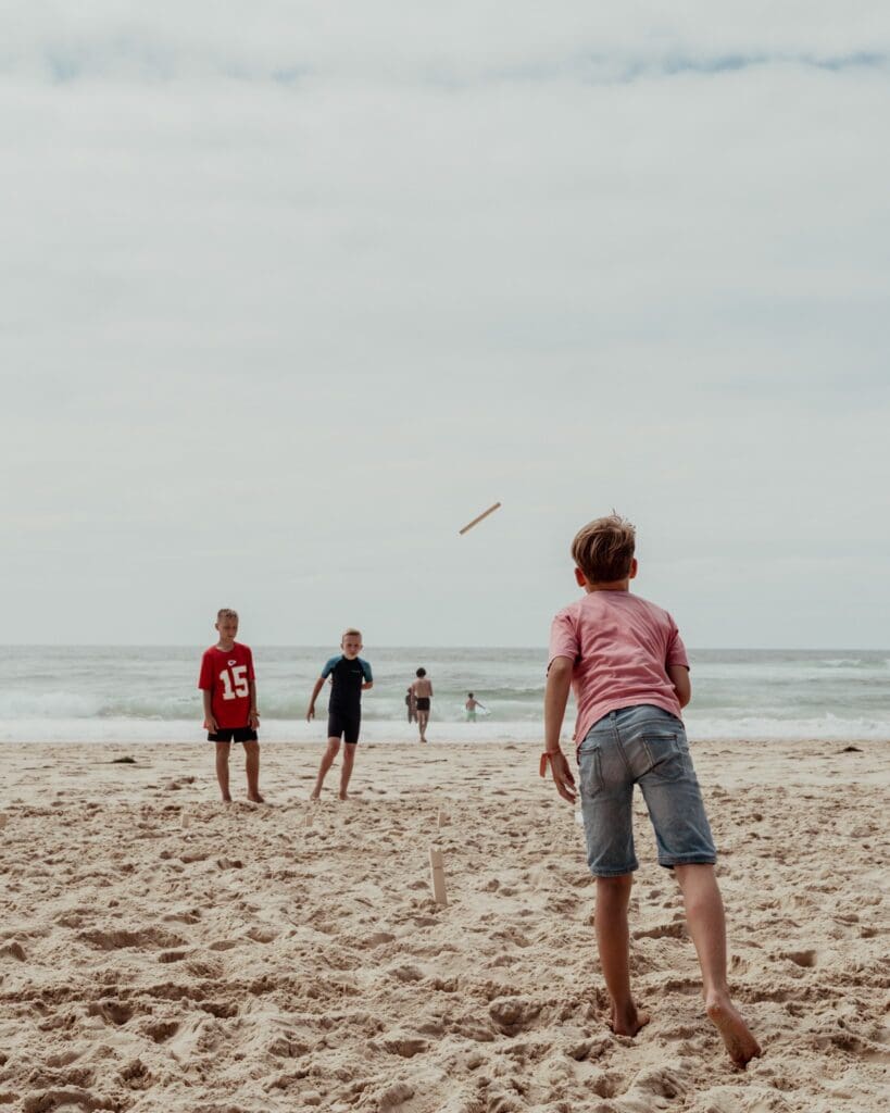 kids playing beach cricket on a cloudy day
